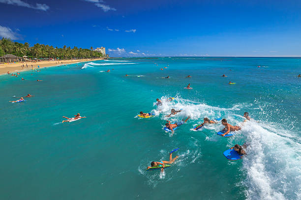 Waikiki, Oahu, Hawaii, United States - August 27, 2016: Boogie boarding, bodyboarding also called, is a popular water sport practiced in Waikiki Beach near the Waikiki Pier at Queens Surf Beach in Honolulu.