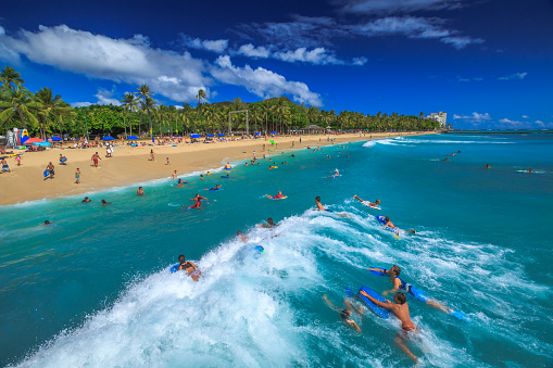 Waikiki, Oahu, Hawaii, United States - August 27, 2016: Body boarding is a popular water sport in Waikiki area. One of best places to board is near the Waikiki Pier at Queens Surf Beach, a section of Waikiki Beach.