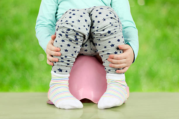 istock Children's legs hanging down from a chamber-pot on a green 619369254