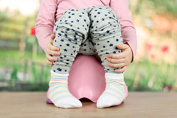 istock Children's legs hanging down from a chamber-pot on a green 619369310