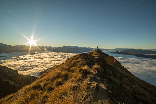 istock Distant young woman hiking stands on a mountain peak 619370698
