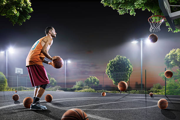 istock Basketball players working out on night court 619370916