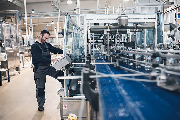 Factory indors. People at work. Smiled happy bearded manual worker doing his job on factory production line for water purification and bottling. bottling plant stock pictures, royalty-free photos & images