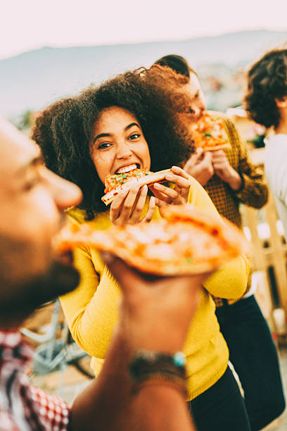 jedzenie pizzy na imprezie na dachu - eating food biting pizza zdjęcia i obrazy z banku zdjęć