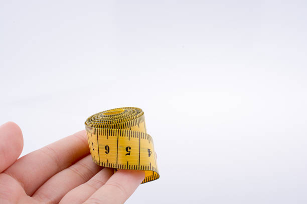 istock Yellow color measuring tape in hand 619380368