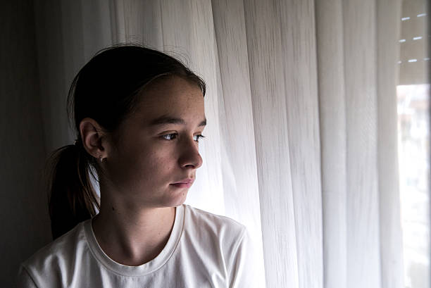 istock sad Girl at home on the Window looking with  pensive 619381050
