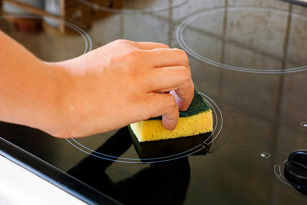 istock Woman hand with sponge cleaning ceramic hob 619383172
