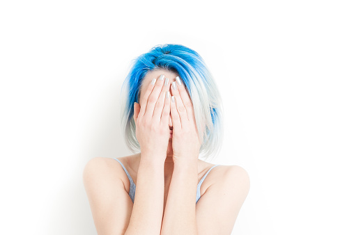 Young teen woman portrait, desperate with hands covering her face, isolated on white background