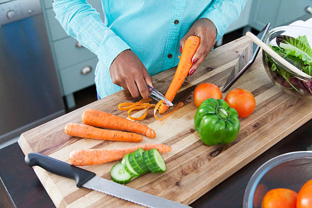 istock African female peeling carrots. 619385188