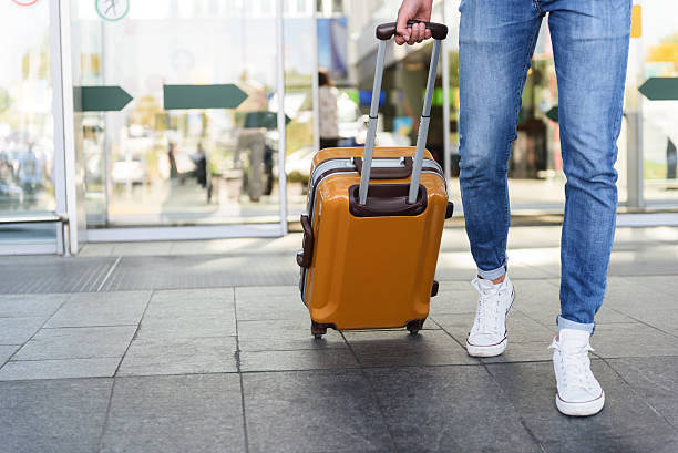 turista maschio che cammina con i bagagli - valigia a rotelle foto e immagini stock