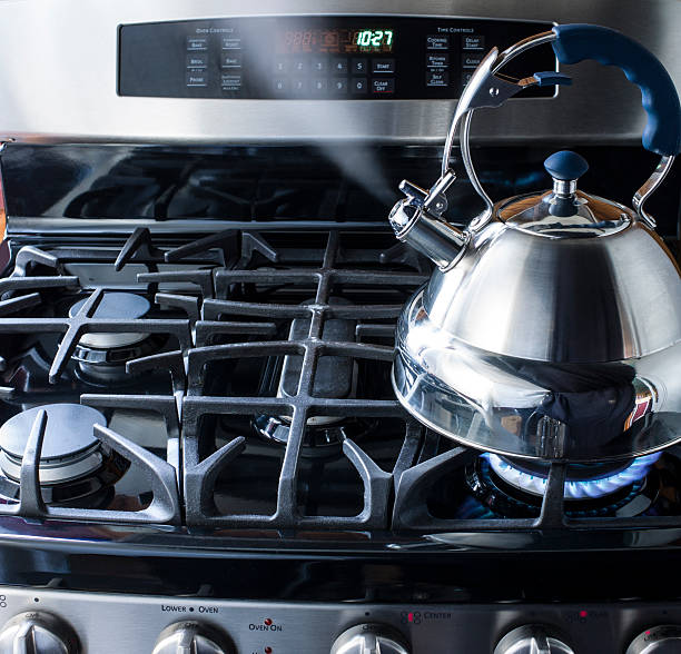 istock Stainless steel kettle steaming on a gas burner stove. 619391832