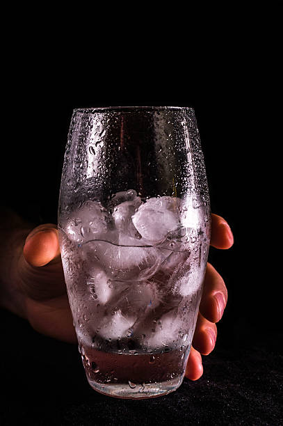 Hand holding glass with water and ice
