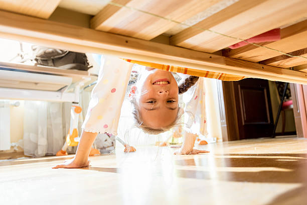 istock little smiling girl looking under bed 619392584
