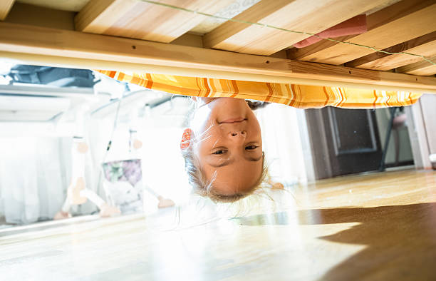 istock Brunette smiling girl looking under bed at morning 619392622
