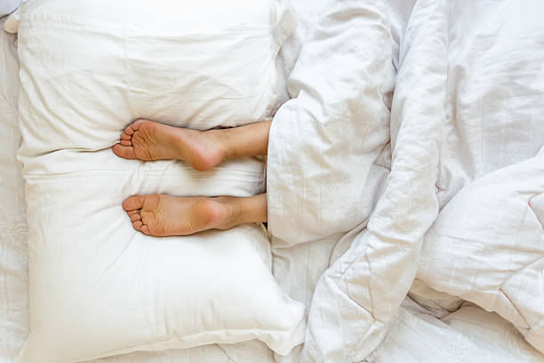 istock Feet lying on soft white pillow at bed 619393288