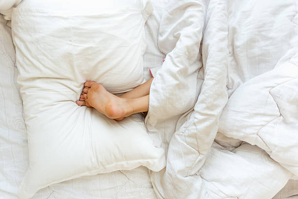 istock Little girl sleeping upside down and holding feet on pillow 619393352
