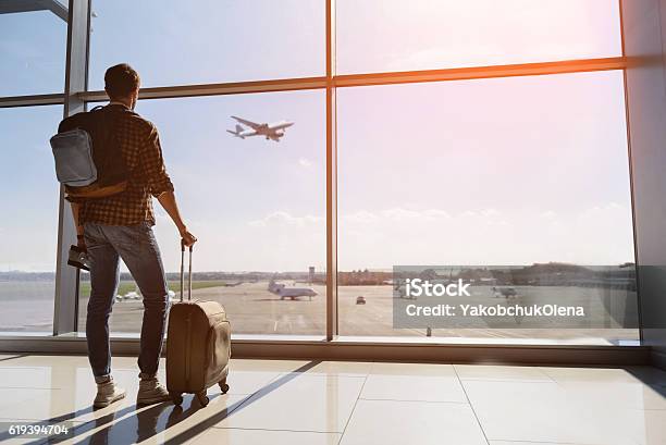 Joven Sereno Viendo El Avión Antes De La Salida Foto de stock y más banco de imágenes de Aeropuerto - Aeropuerto, Avión, Pasajero