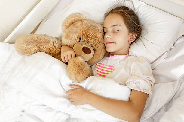 istock Cute girl sleeping and hugging big teddy bear at bed 619395694