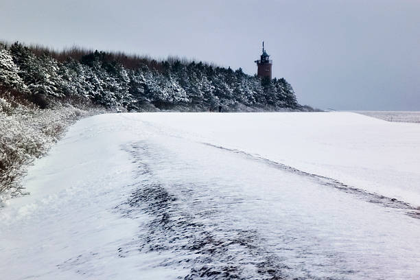 Dark landscape photo of mole (pier) covered of snow with frozen lake on background - winter time
