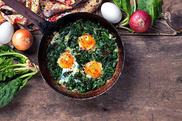 Braised spinach and eggs in an old frying pan Braised spinach and eggs in an old frying pan omelet rustic food food and drink stock pictures, royalty-free photos & images