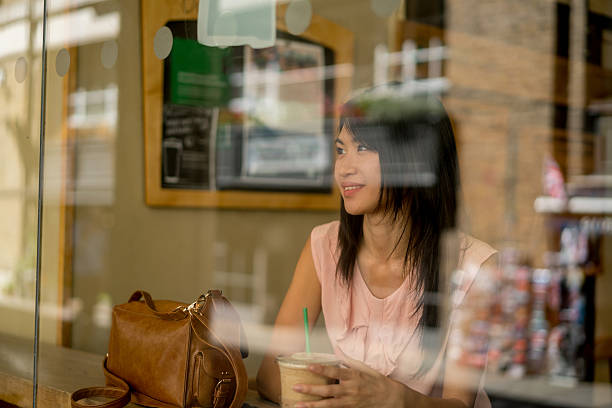 istock Asian woman having an iced coffee at a cafe 619403754