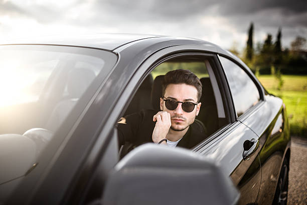istock fashion man driving a black car 619405972