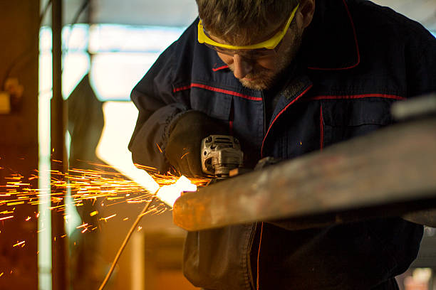 istock Manual worker grinding steel table in production hall. 619407646