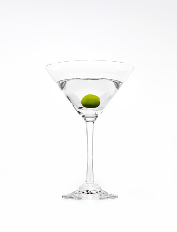 Vodka pouring out of a bottle into a martini glass with an olive.