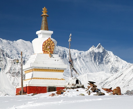 View of white buddhist stupa near ice lake (Kicho Tal) and mount Khangsar Kang, Annapurna range, Nepal