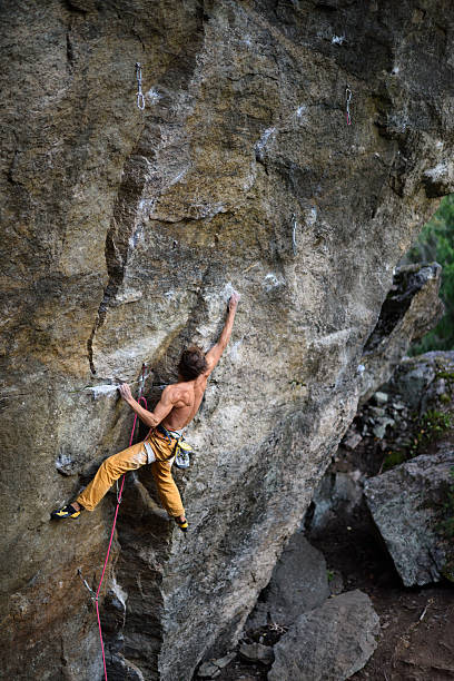 若い男がベレーと岩を登る。 - conquering adversity endurance adventure danger ストックフォトと画像