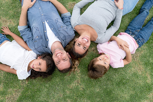 Portrait of a happy Latin American family outdoors lying on the floor and looking at the camera smiling