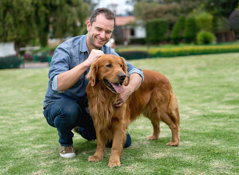 Casual man walking his dog at the park and looking very happy - lifestyle concepts
