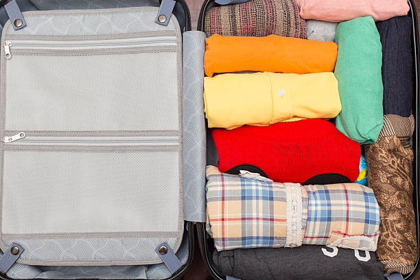 istock Open suitcase with clothing on wood table 619497622