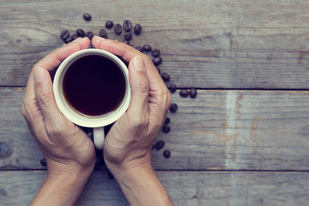 istock Female hands holding cup with coffee beans 619497688