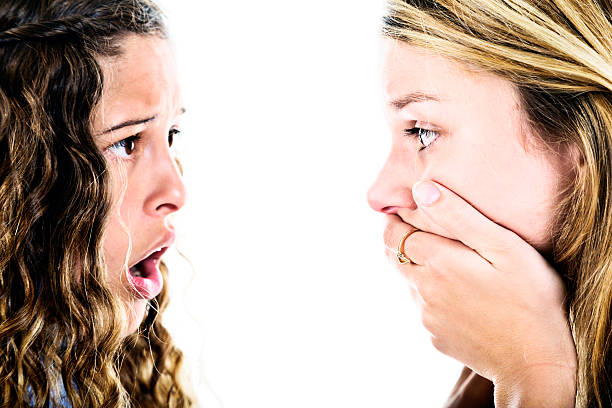 bad news! two shocked girls look at each other, horrified - gasping color image hands covering mouth staring imagens e fotografias de stock