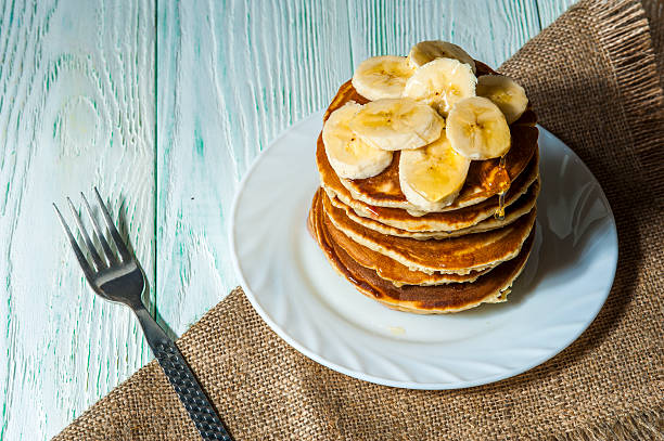 Sweet pancakes with banana slices on white plate
