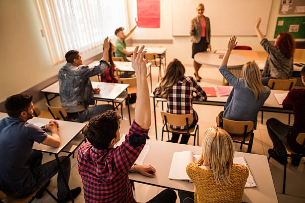 istock Students in the classroom raising hands to answer teacher's question. 619505296