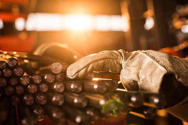 Close up of unrecognizable worker with stack of metal tubes. Close up of unrecognizable person with protective gloves working with large group of metal tubes. metallurgy stock pictures, royalty-free photos & images