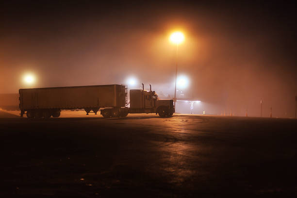 istock Midnight Interstate Expressway Foggy Rest Stop Parked Trailer Truck 619505720