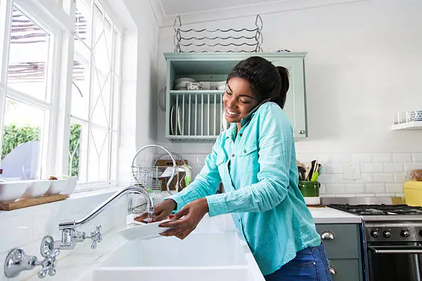 Photo of African female doing the dishes.
