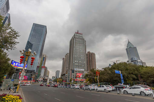 Urumqi, Xinjiang, China - October 14, 2016: Urumqi downtown street view. Office buildings on the background, Cars and incidental people at front.