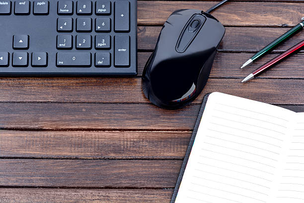 istock Notebook with pen and keyboard on wooden background 619507960