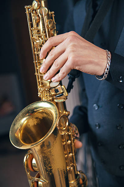 istock Young man in a suit hold saxophone 619511530
