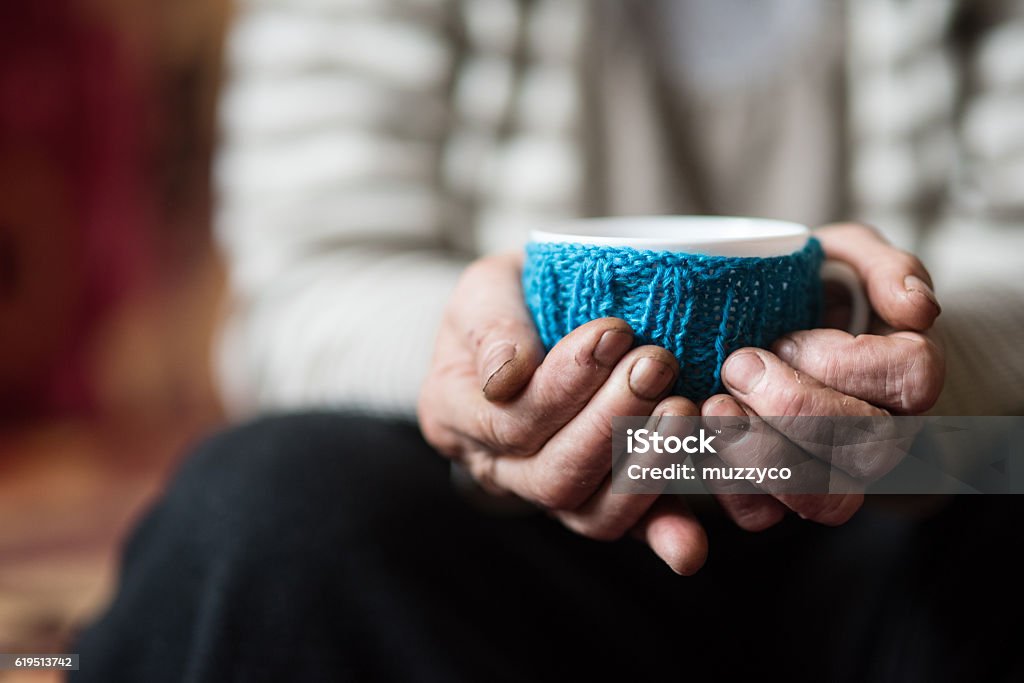 Cup of tea in tired hands of woman Elderly woman holding cup of hot coffee or tea Cold Temperature Stock Photo