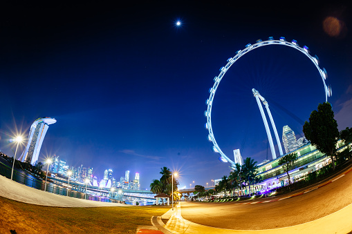 The famous ferris wheel (Flyer) and Singapore Skyline at Marina bay shot with a fisheye-lens at night. Long exposure.