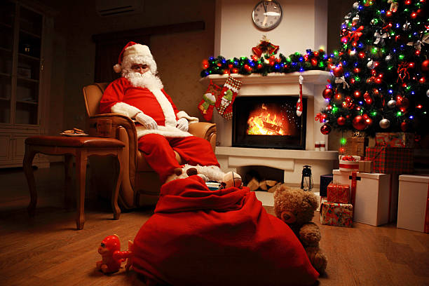 istock Santa Claus having rest in chair near  fireplace at home 619516708