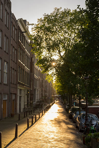 Street along a canal in Amsterdam with traditional old buildings facades at to the canals in Amsterdam, the capitol of The Netherlands. The ancient merchant's houses are located at the ring of canals in the city centre.