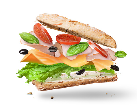 Ciabatta Sandwich with Lettuce, Tomatoes, Ham and Cheese cutted in half flying in the air