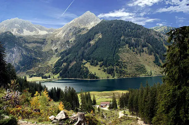 Mountain lake in Tannheim Valley in Tirol, Austria; steep mountains, spruces and shrubs, day in autumn