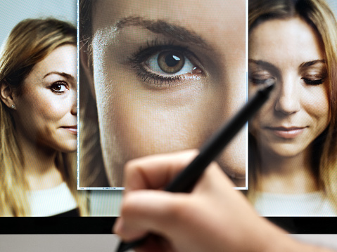 Image of  a hand with professional digital tablet retouching and editing multiple digital photographs of a beautiful woman. Sharp focus on screen. Horizontal image from a DSLR camera.